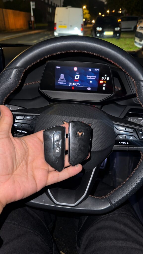 Two Cupra key fobs held in front of the steering wheel and instrument display.