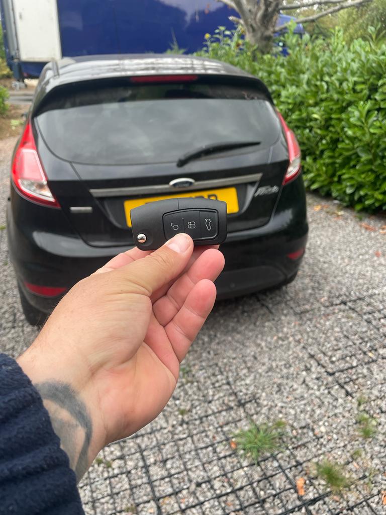 Ford Fiesta flip car key beside a black Ford Fiesta, showing a vehicle key replacement example